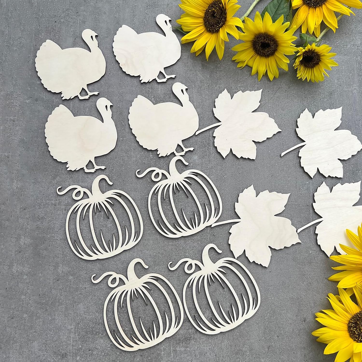 White paper cutouts of turkeys, pumpkins, and leaves on a gray background with sunflowers.