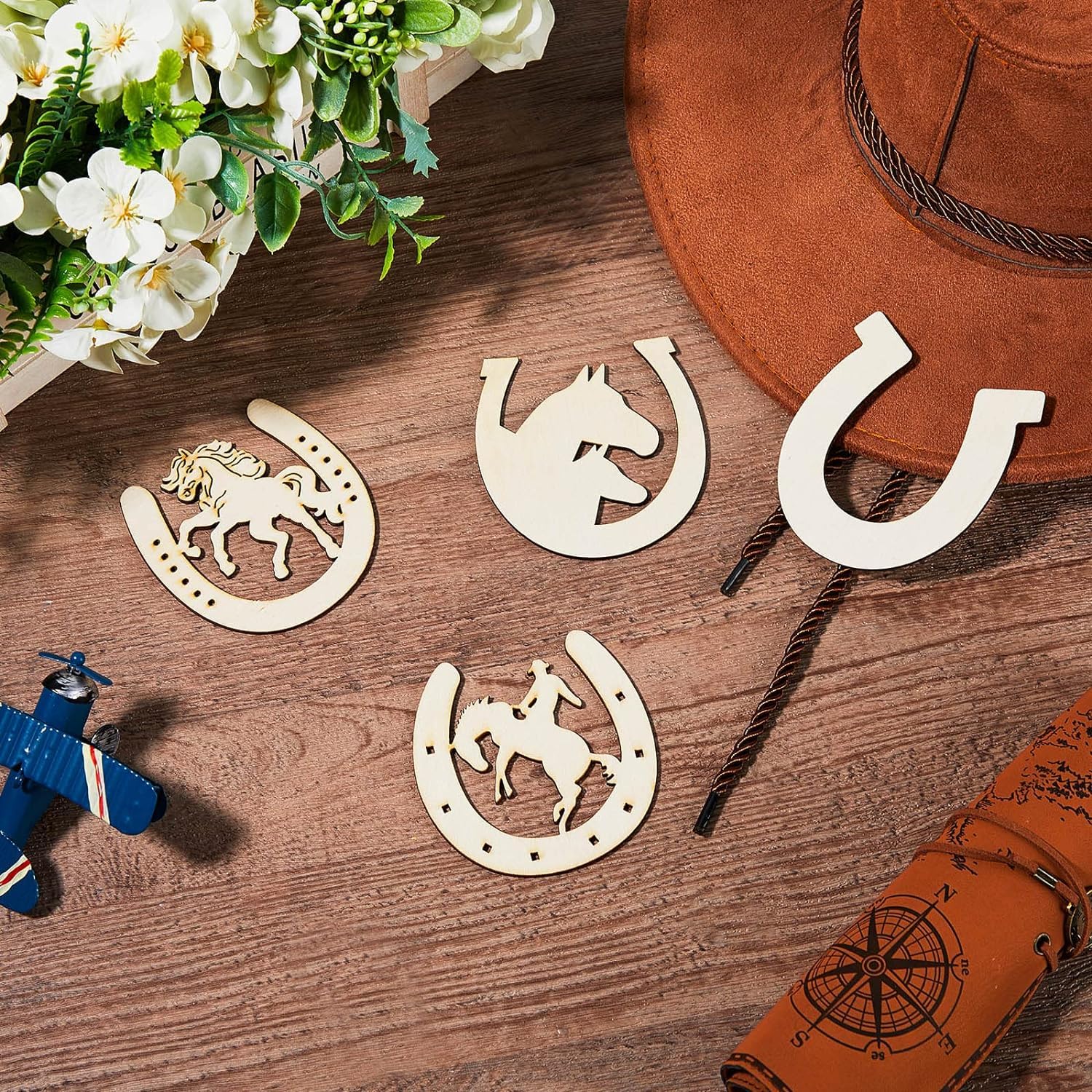 Decorative horse and horseshoe shapes on a wooden surface with a hat and flowers.