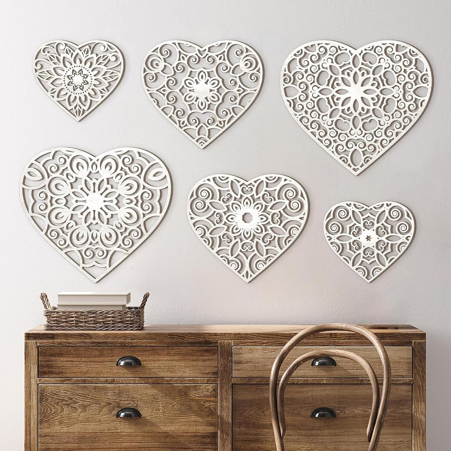 Decorative heart-shaped wall art pieces on a plain wall above a wooden console table.