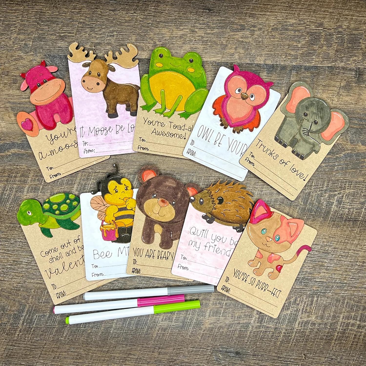 Valentine's Day cards with animal illustrations on a wooden surface