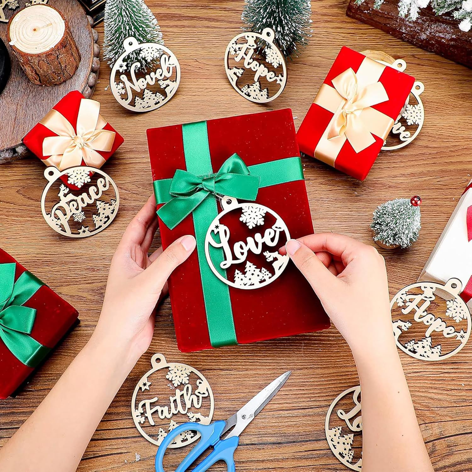 Person decorating a gift with Christmas-themed cutouts on a wooden surface.