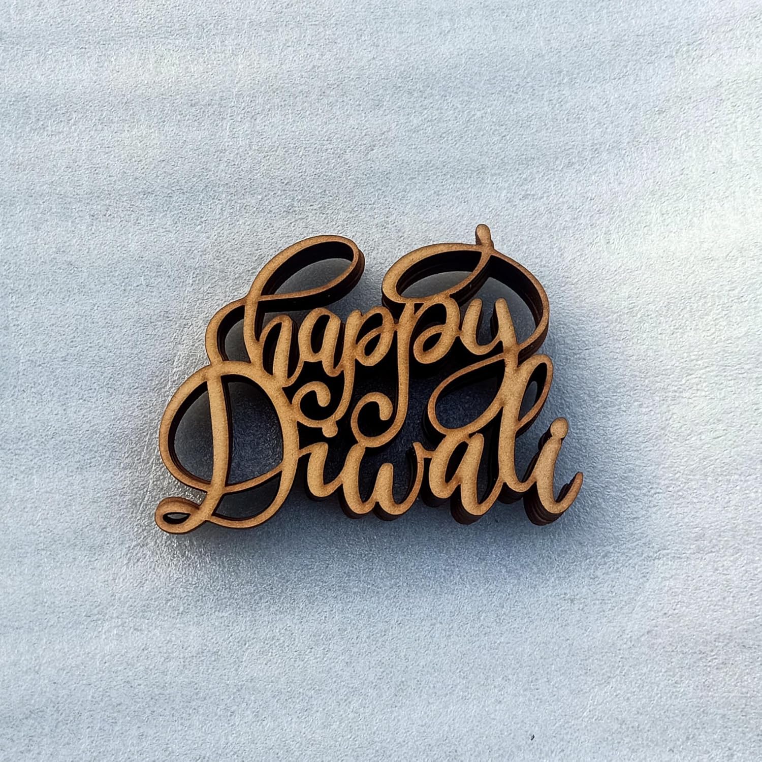 Wooden 'Happy Diwali' decoration on a light blue background