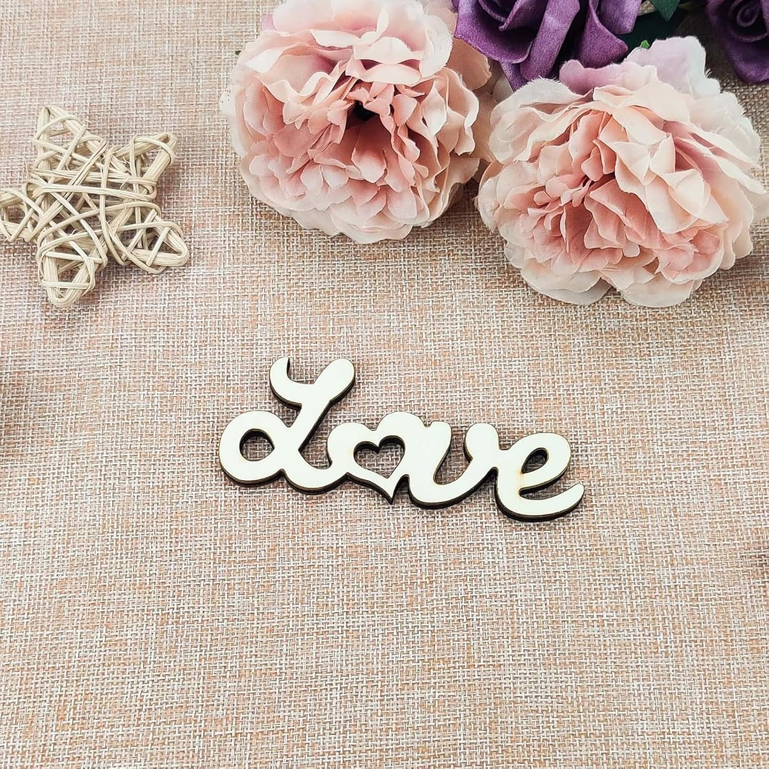 Wooden 'love' sign with pink flowers and a butterfly on a textured surface