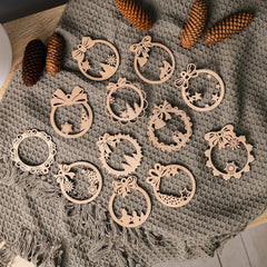 Decorative wooden ornaments on a textured fabric surface with pine cones.