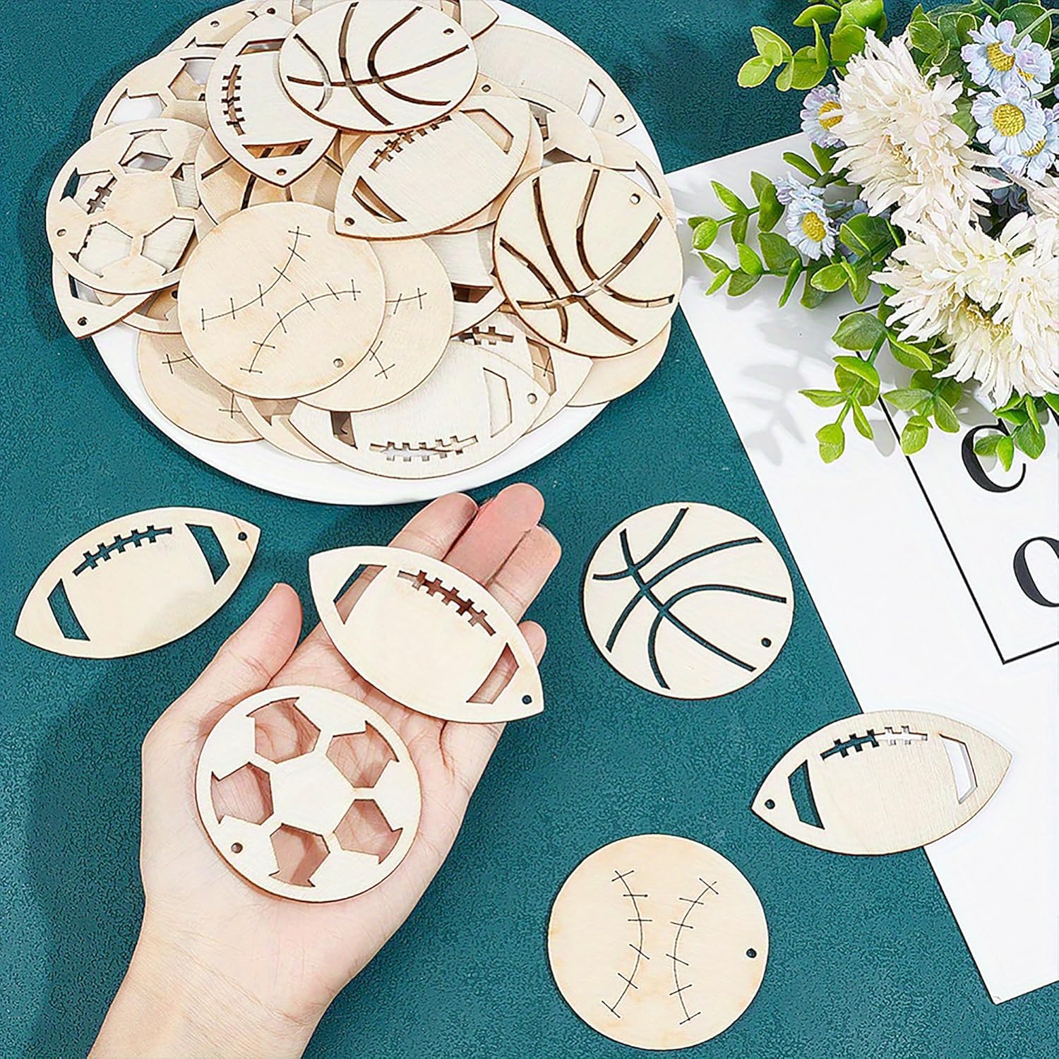 Wooden sports-themed coasters on a teal surface with a hand holding one coaster.