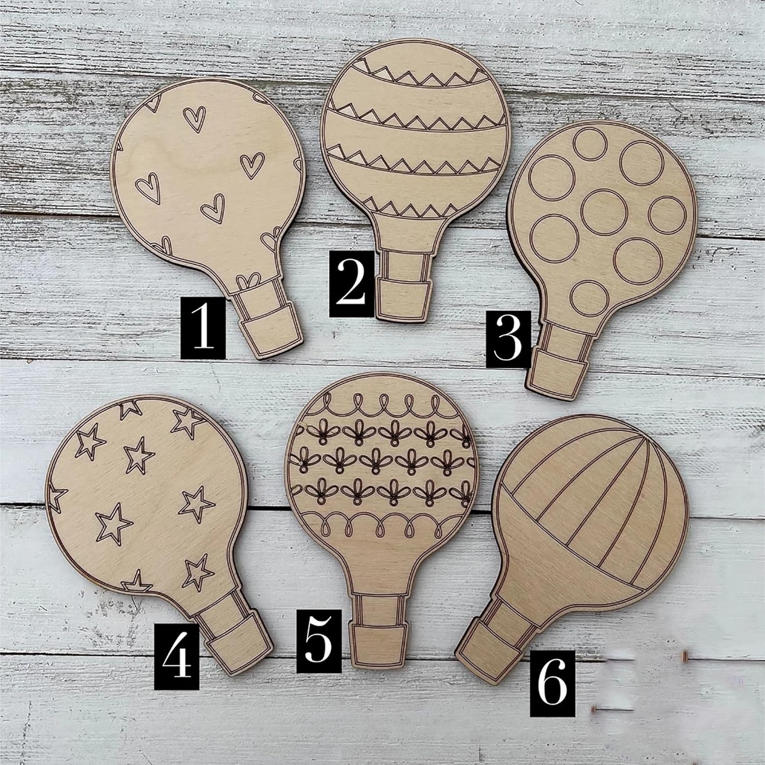 Six wooden hot air balloon-shaped cutouts with different patterns on a wooden surface.