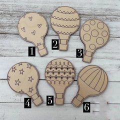 Six wooden hot air balloon-shaped cutouts with different patterns on a wooden surface.