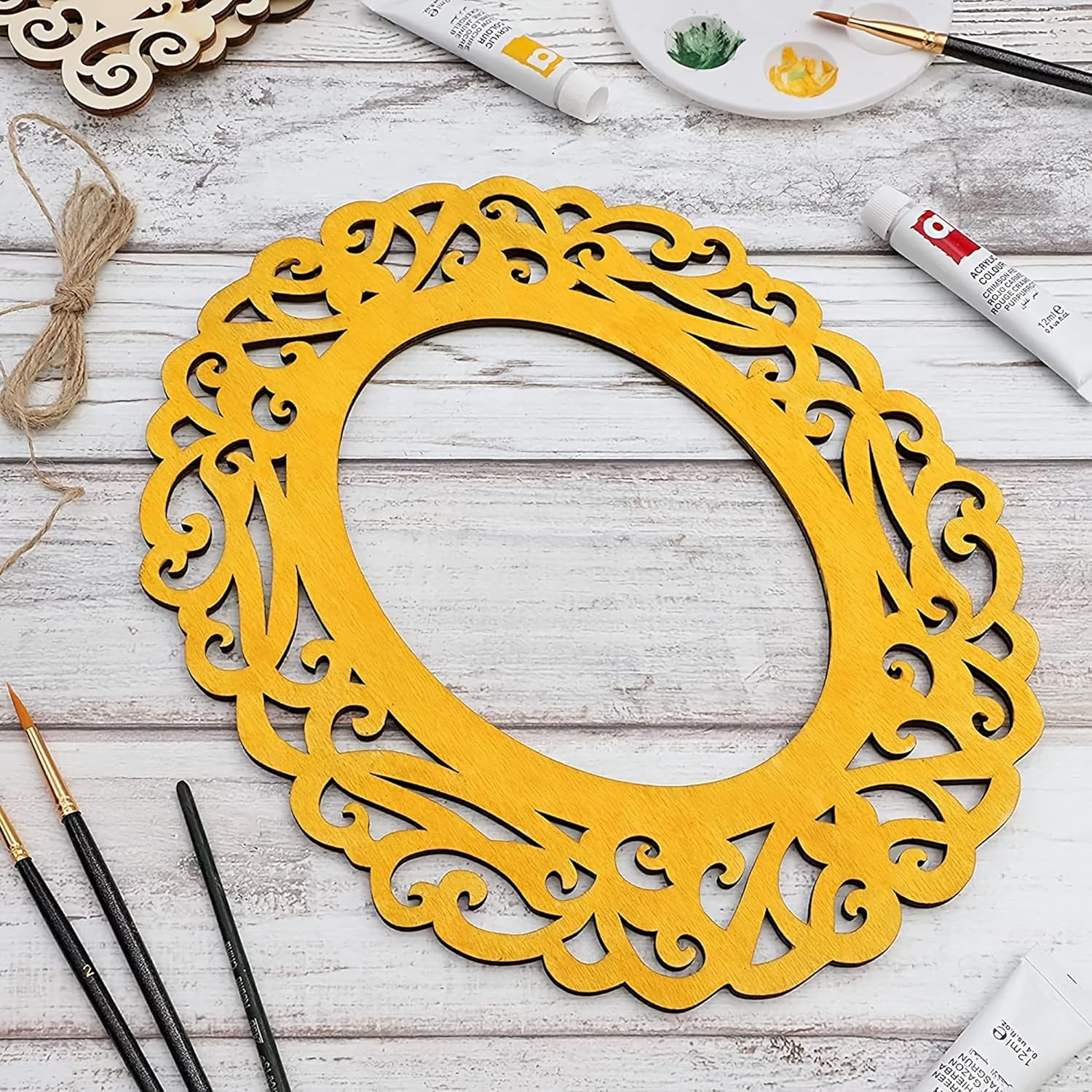 Yellow decorative circular frame on a wooden surface with painting supplies.