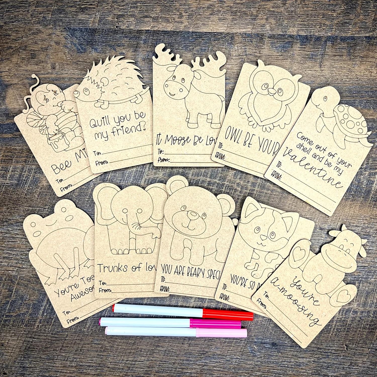 Coloring cards with animal illustrations and markers on a wooden surface