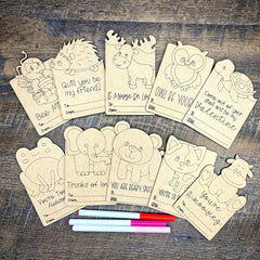 Coloring cards with animal illustrations and markers on a wooden surface
