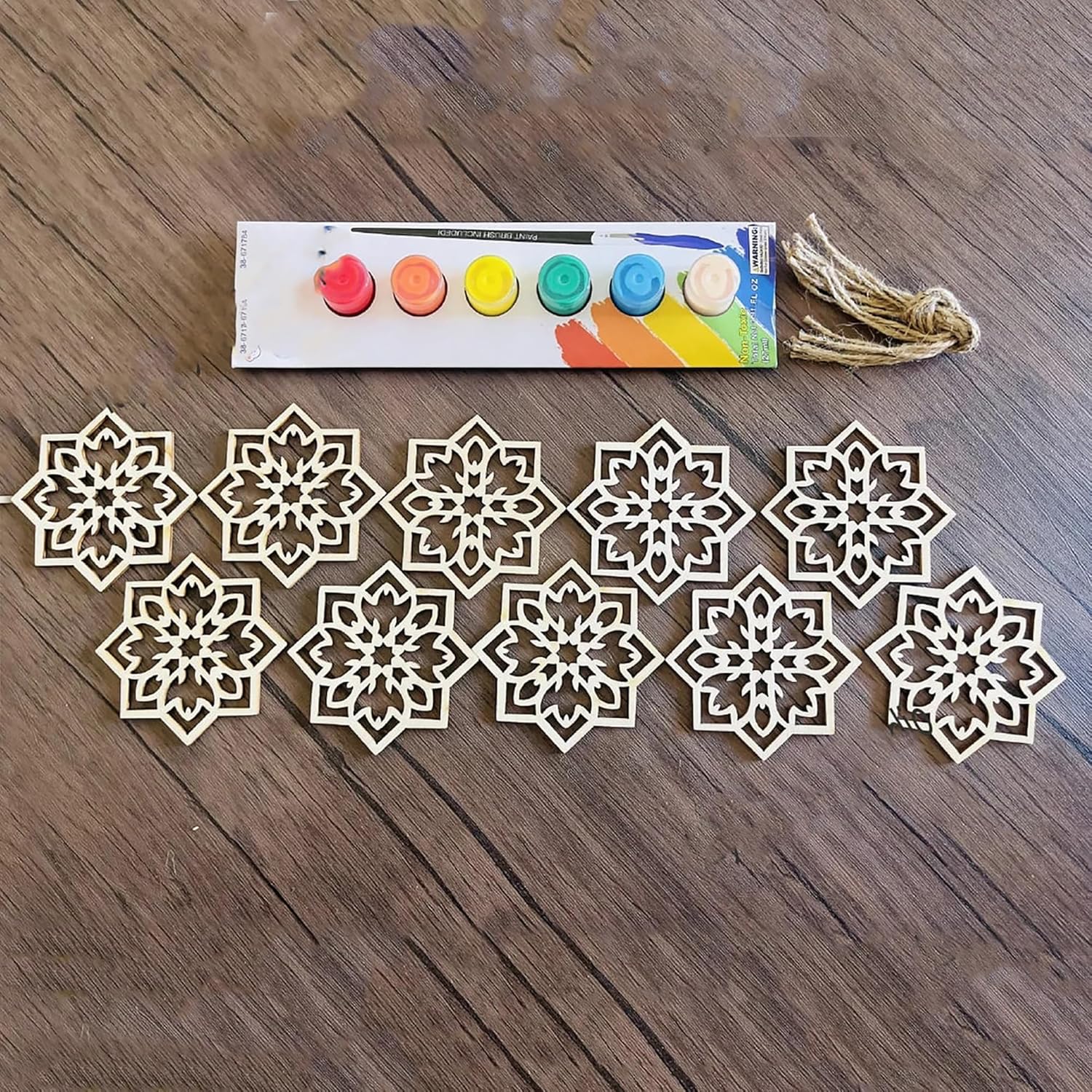 Decorative snowflake cutouts and a set of paint colors on a wooden surface