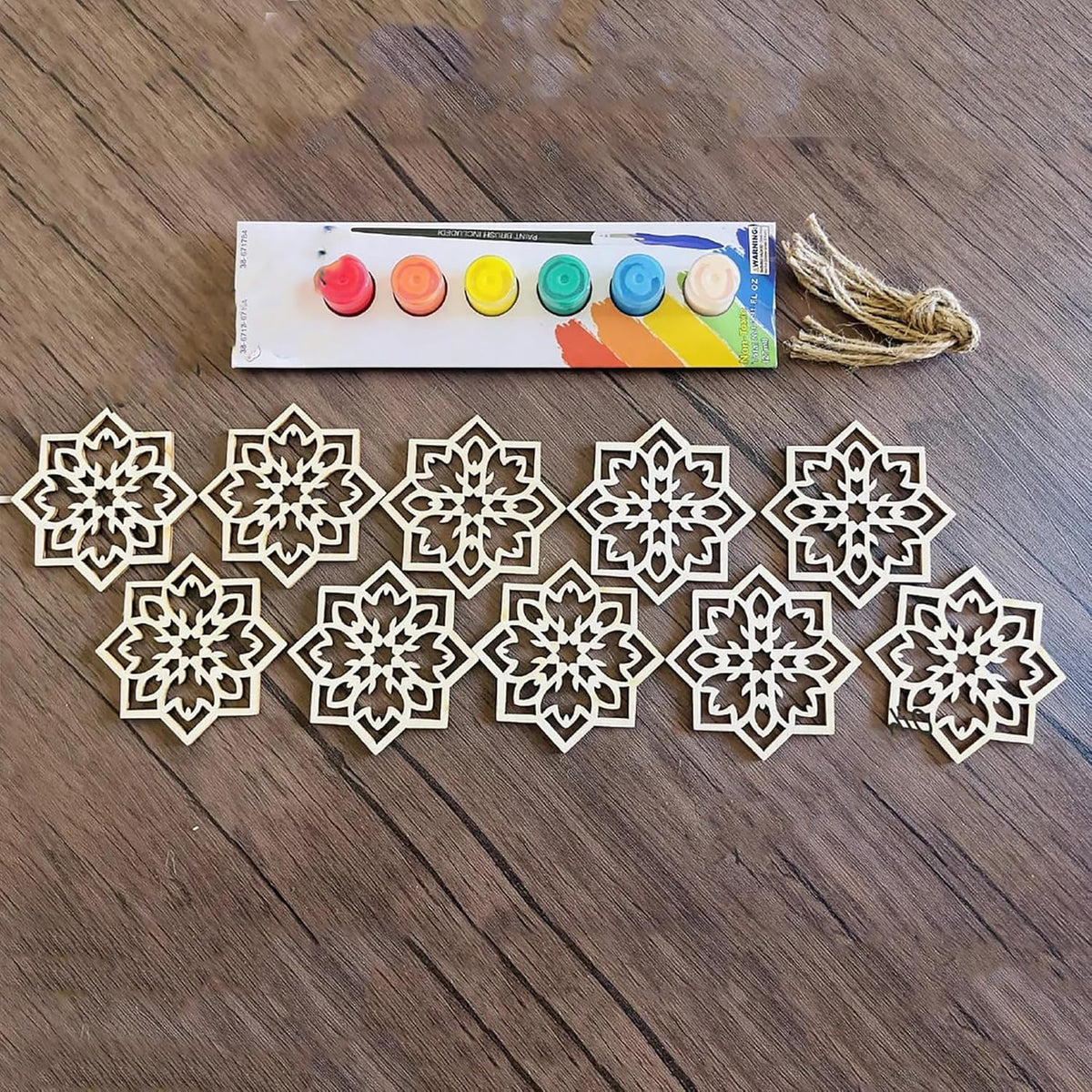 Decorative snowflake cutouts and a set of paint colors on a wooden surface