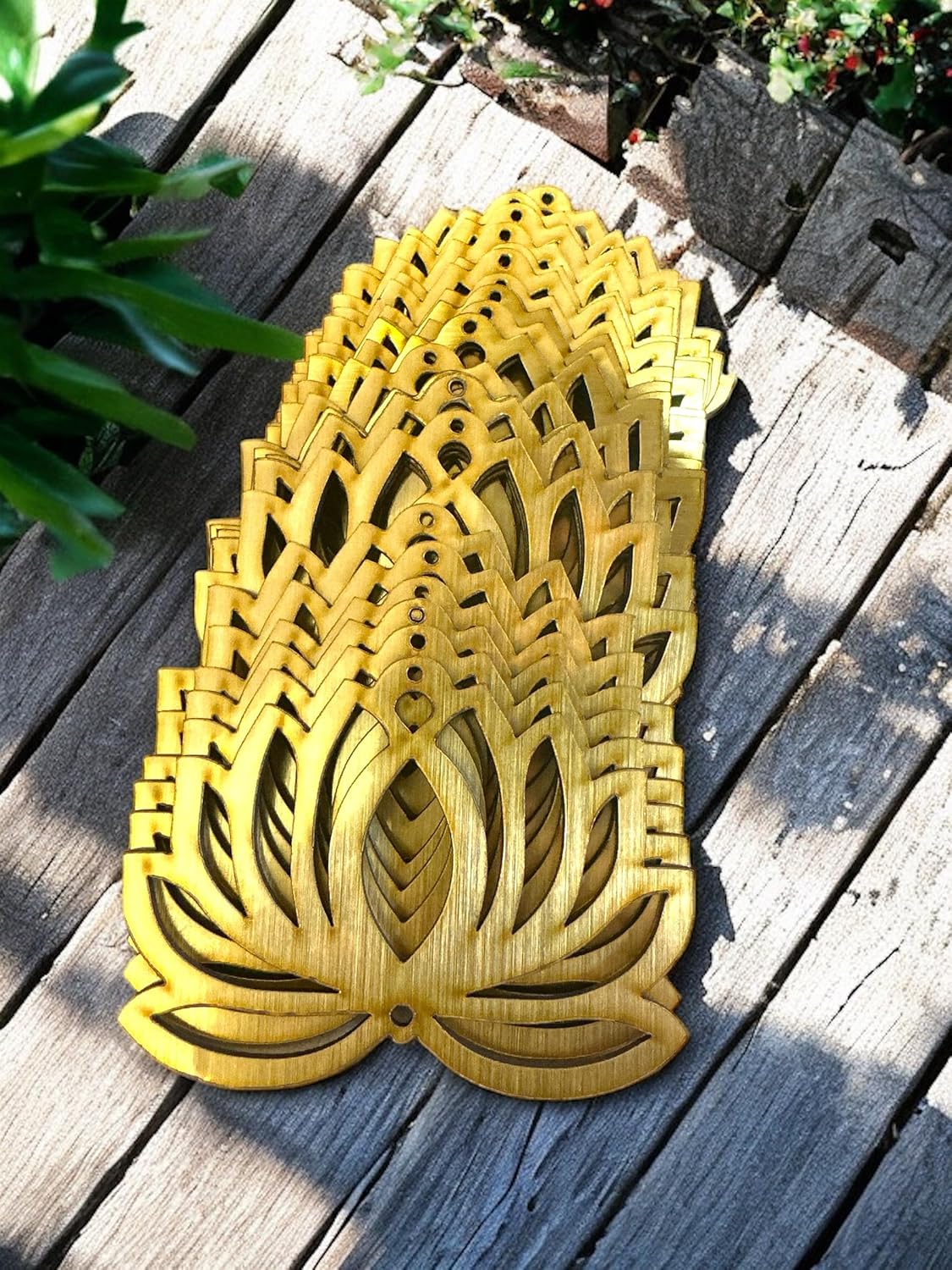 Decorative wooden pineapple on a wooden surface with plants in the background