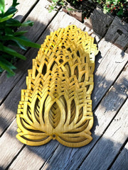 Decorative wooden pineapple on a wooden surface with plants in the background