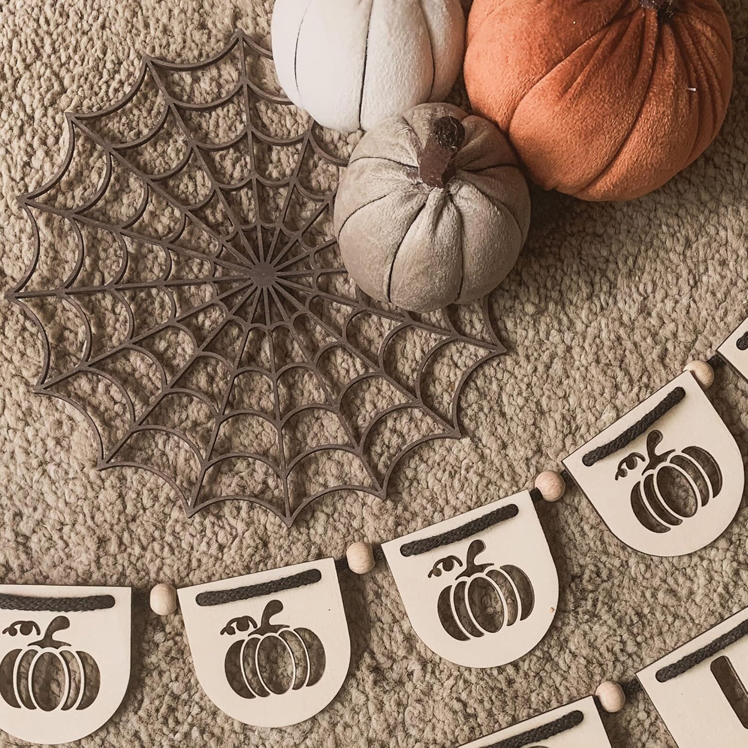 Decorative banner with pumpkin designs and a spiderweb on a textured surface.