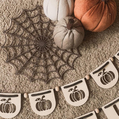 Decorative banner with pumpkin designs and a spiderweb on a textured surface.