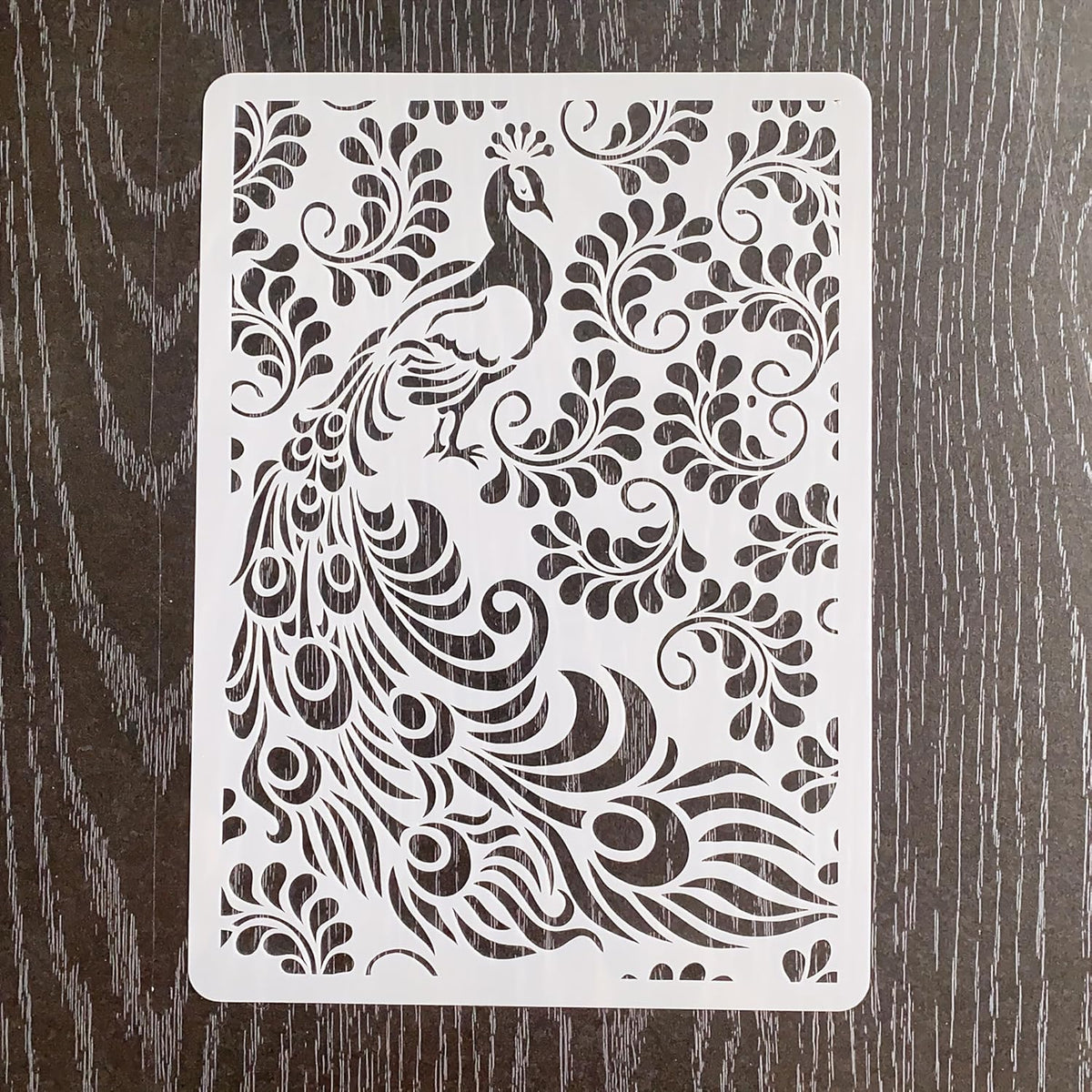 Decorative stencil with peacock design on a wooden surface