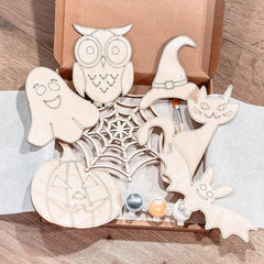 Set of Halloween-themed wooden decorations including a ghost, owl, witch hat, cat, and pumpkin on a spiderweb design.