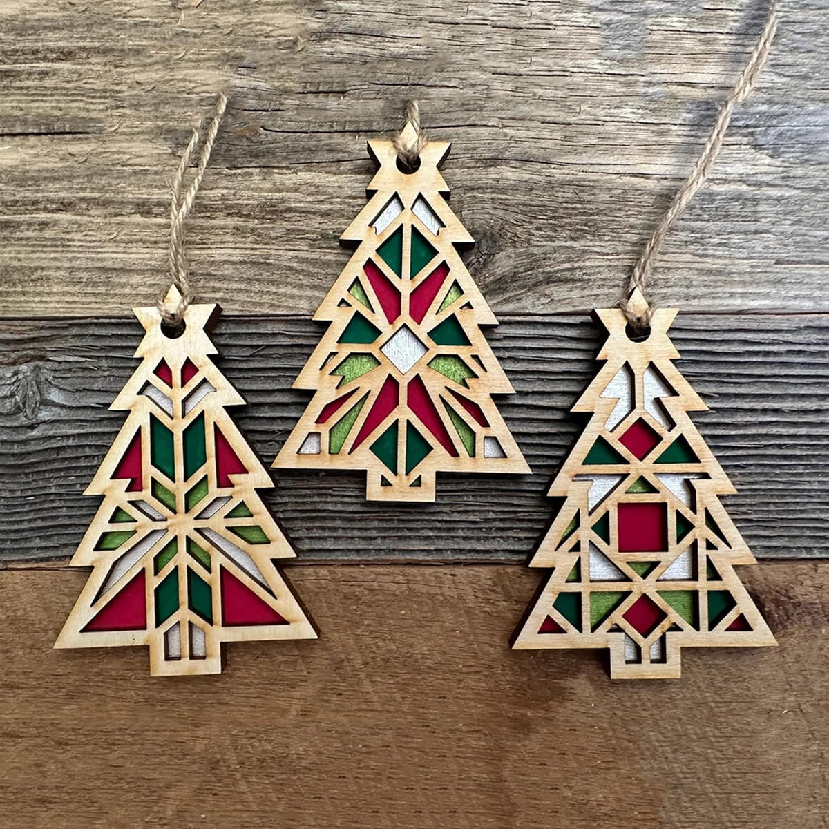 Three geometric Christmas tree ornaments on a wooden surface