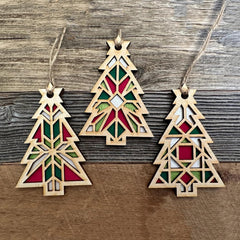 Three geometric Christmas tree ornaments on a wooden surface