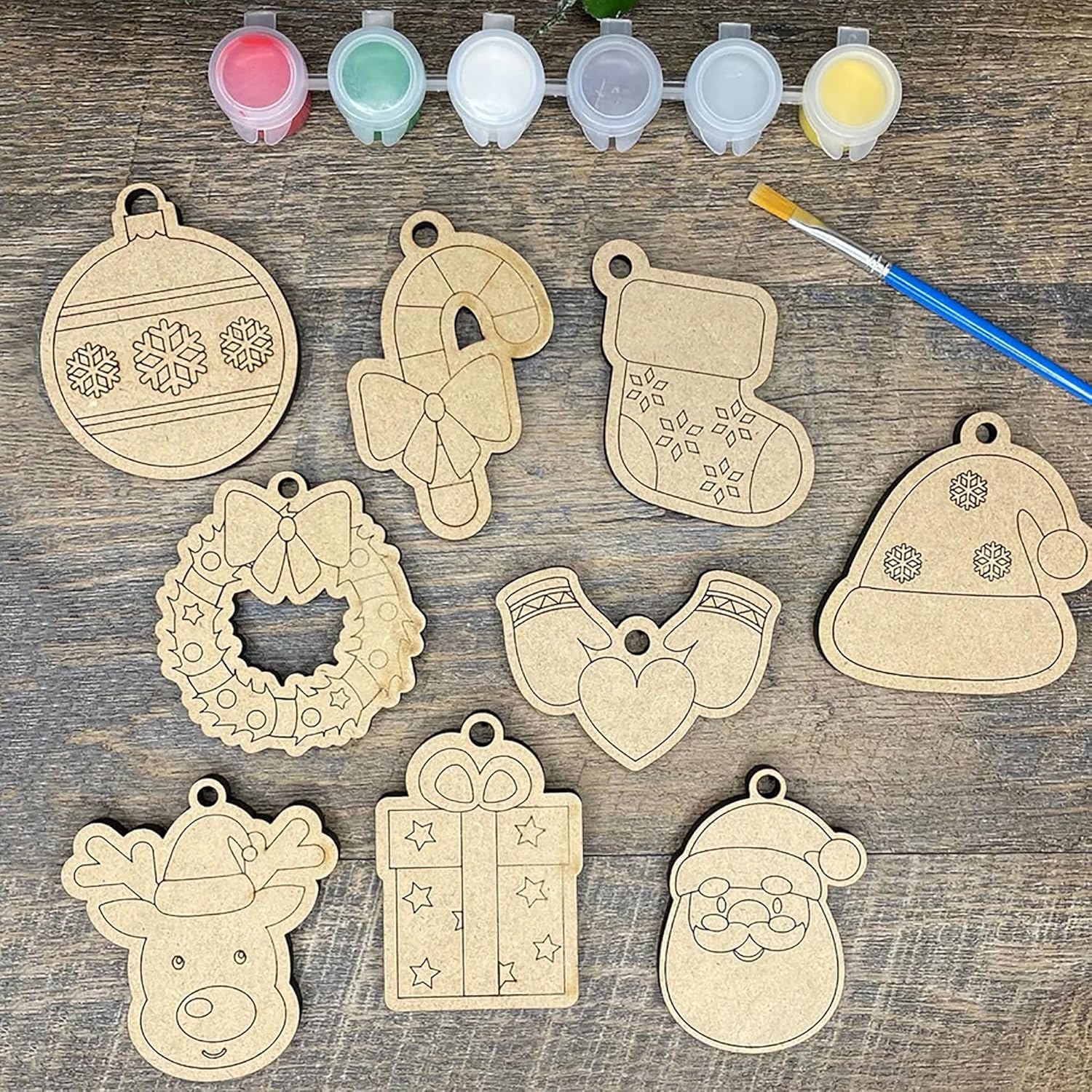 Wooden Christmas ornaments with paint containers and a brush on a wooden surface