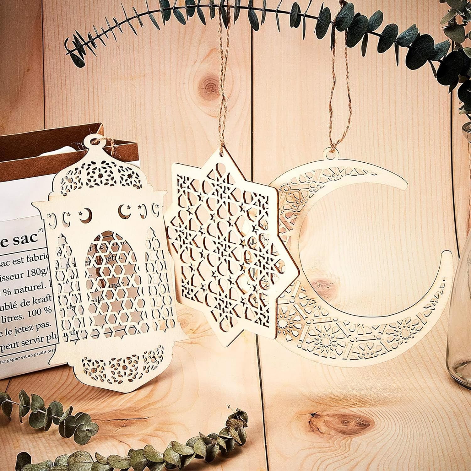 Decorative metal hanging ornaments on a wooden surface with eucalyptus leaves.