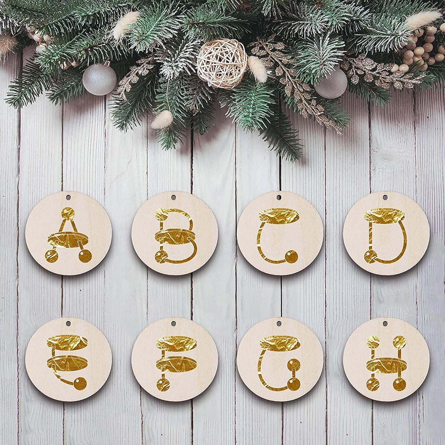 Set of round wooden ornaments with gold designs on a wooden surface with Christmas decorations.