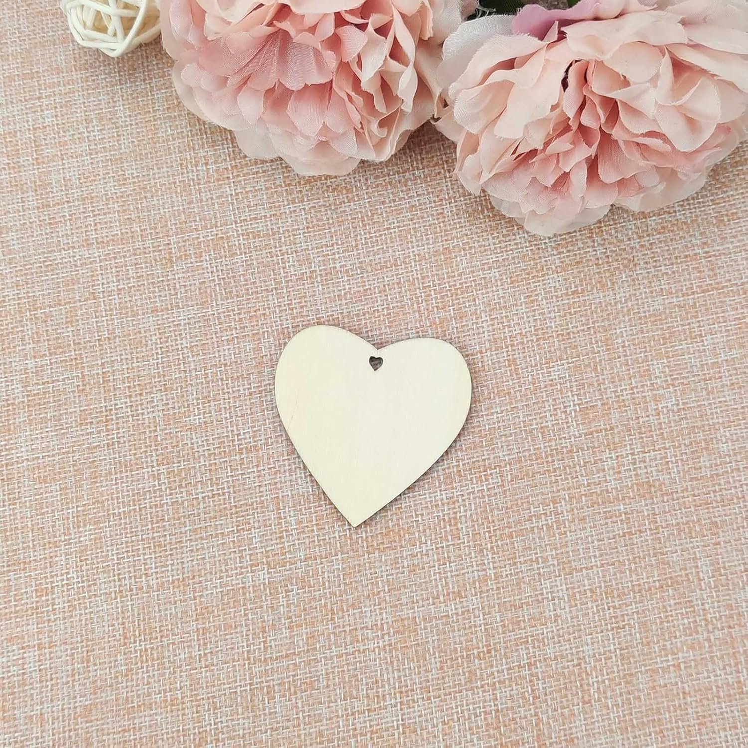 Heart-shaped tag on a textured beige surface with pink flowers in the background