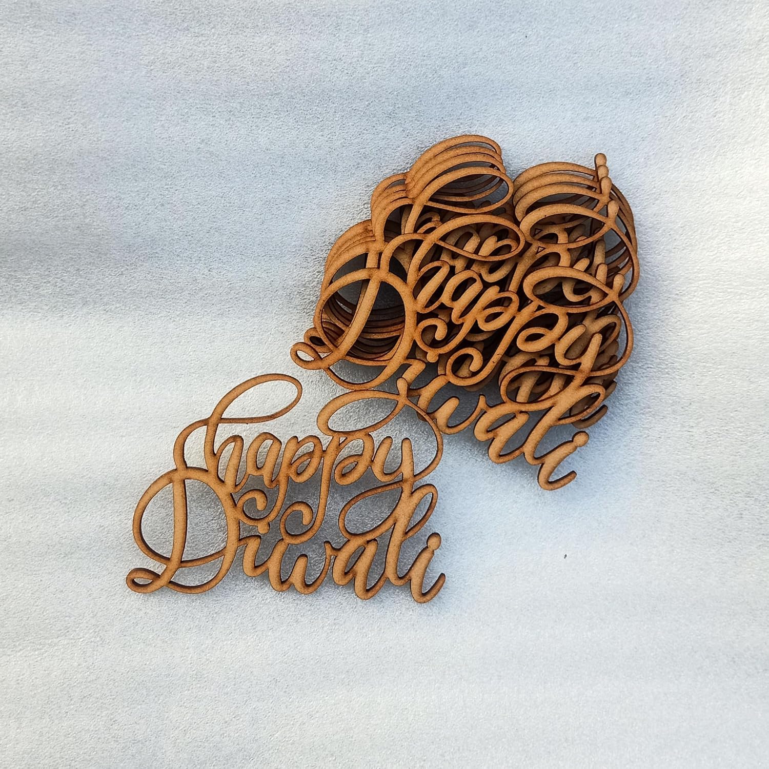Wooden decorative piece with 'Happy Diwali' text on a light background