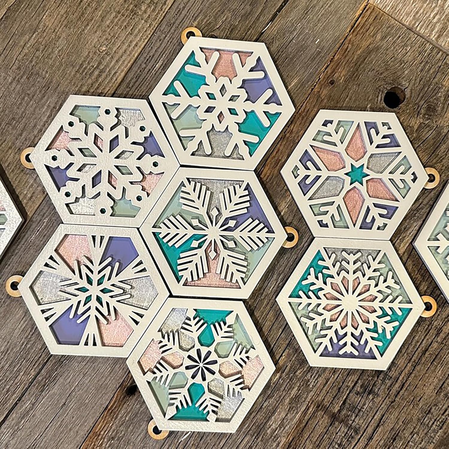 Hexagonal snowflake coasters with multicolored patterns on a wooden surface