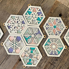 Hexagonal snowflake coasters with multicolored patterns on a wooden surface