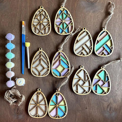 Decorative earrings with geometric designs on a wooden surface, accompanied by tools.