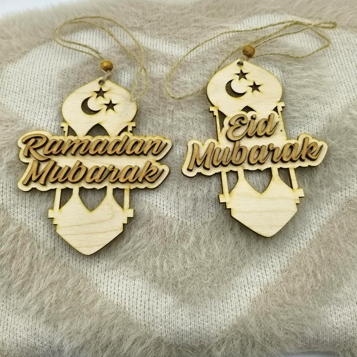 Two wooden ornaments with 'Ramadan Mubarak' and 'Eid Mubarak' text on a textured surface.