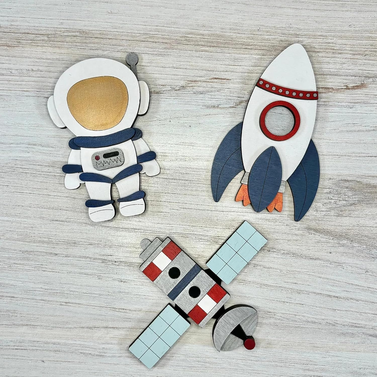 Wooden space-themed toys including an astronaut, a rocket, and a spaceship on a wooden surface.