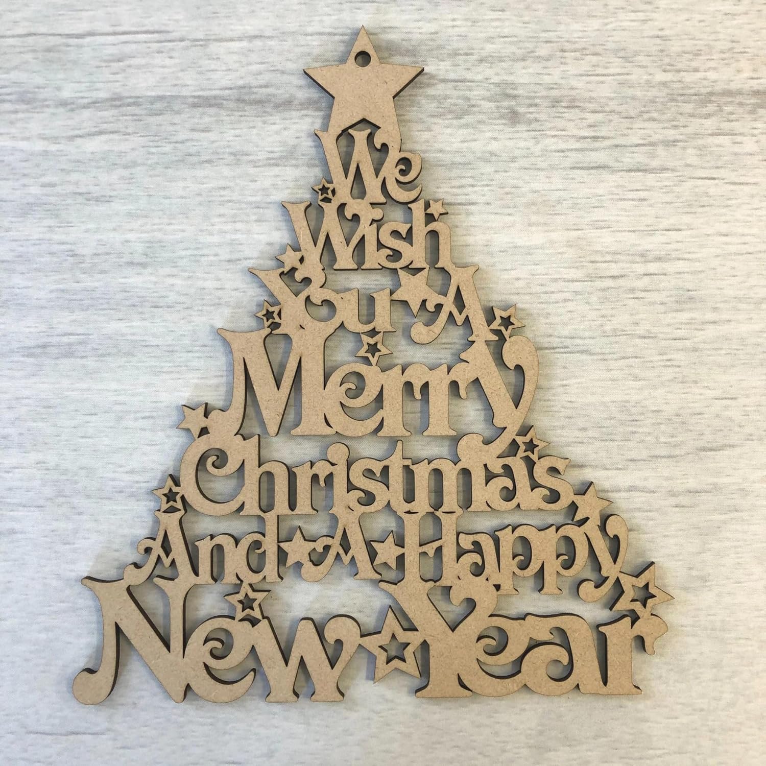 Wooden Christmas tree decoration with engraved text on a light wooden background