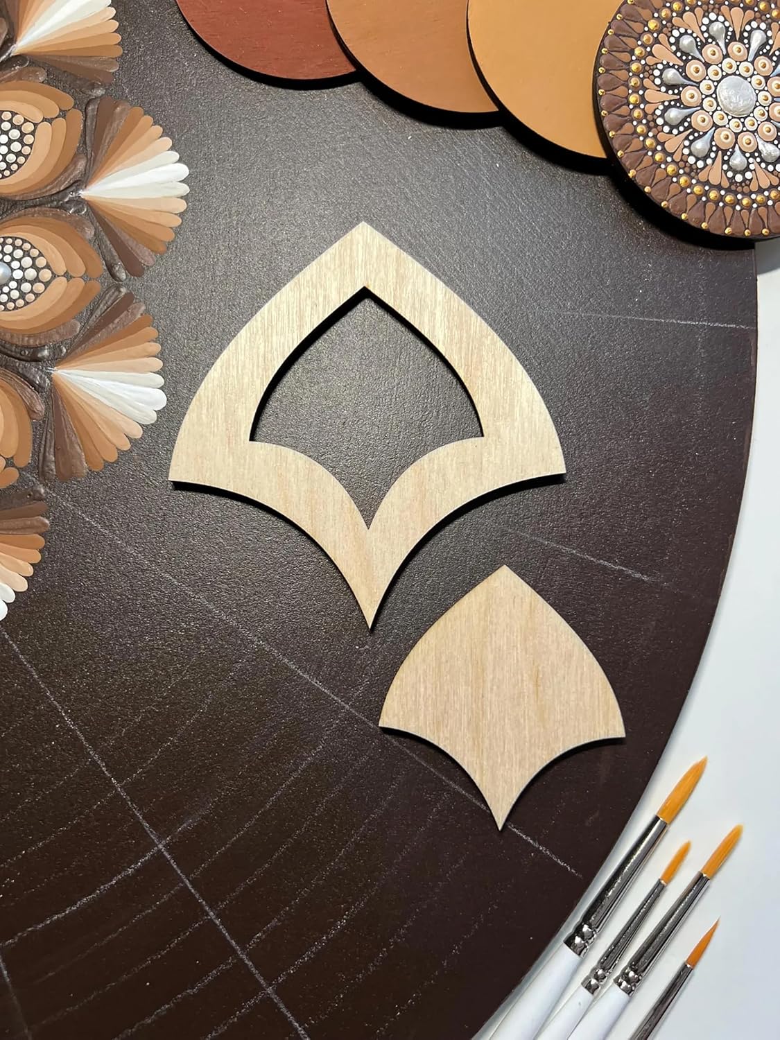 Wooden decorative cutout on a textured surface with color swatches and paintbrushes.