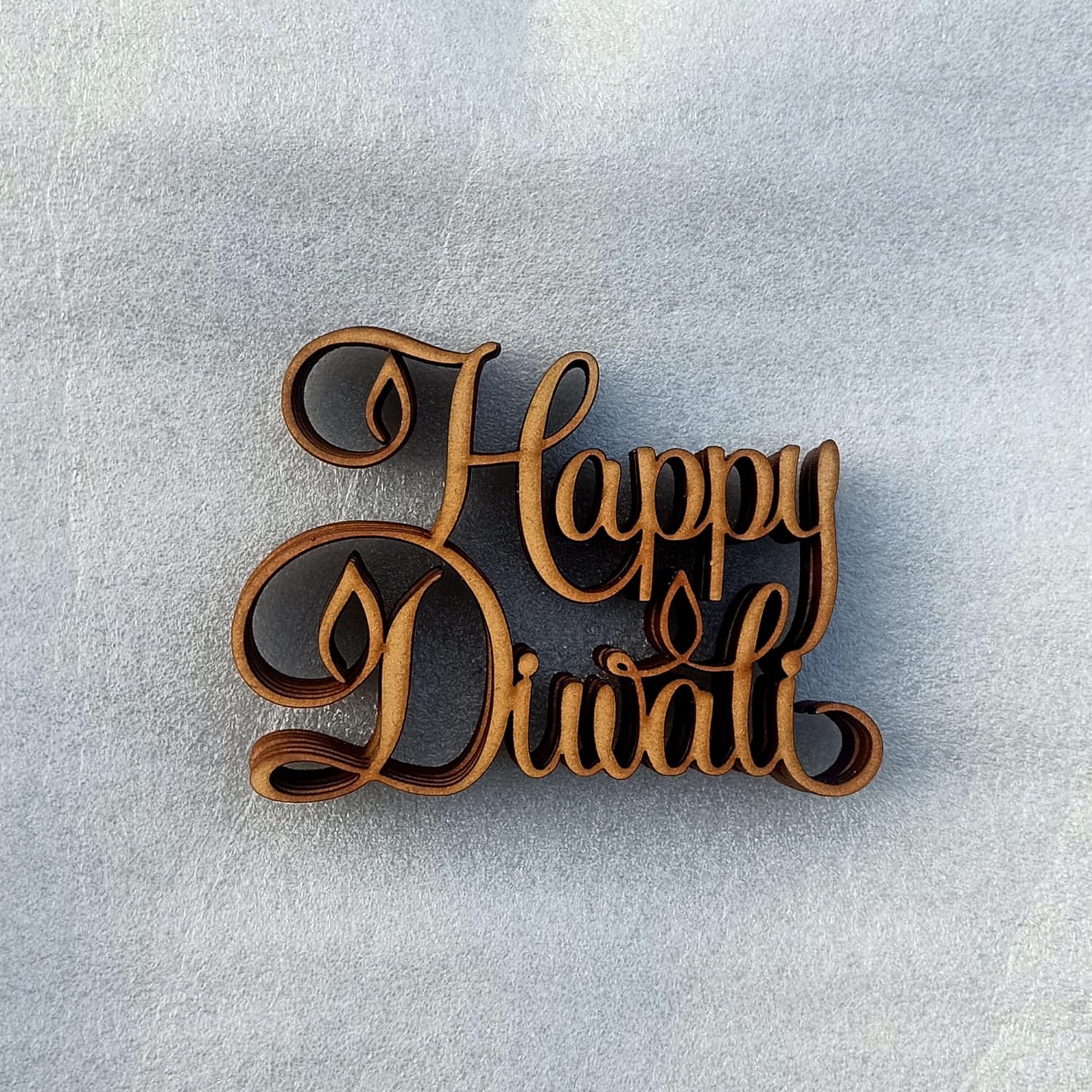 Wooden decorative sign with 'Happy Diwali' text on a light gray background
