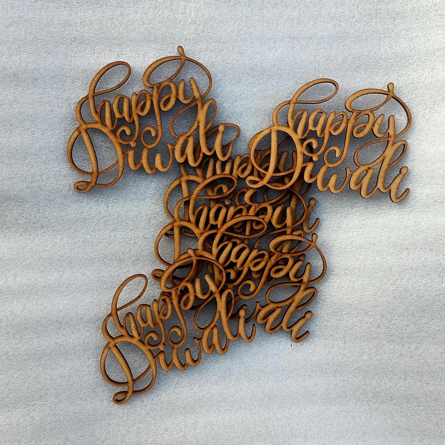 Wooden cutout letters spelling 'Happy Diwali' on a light gray background