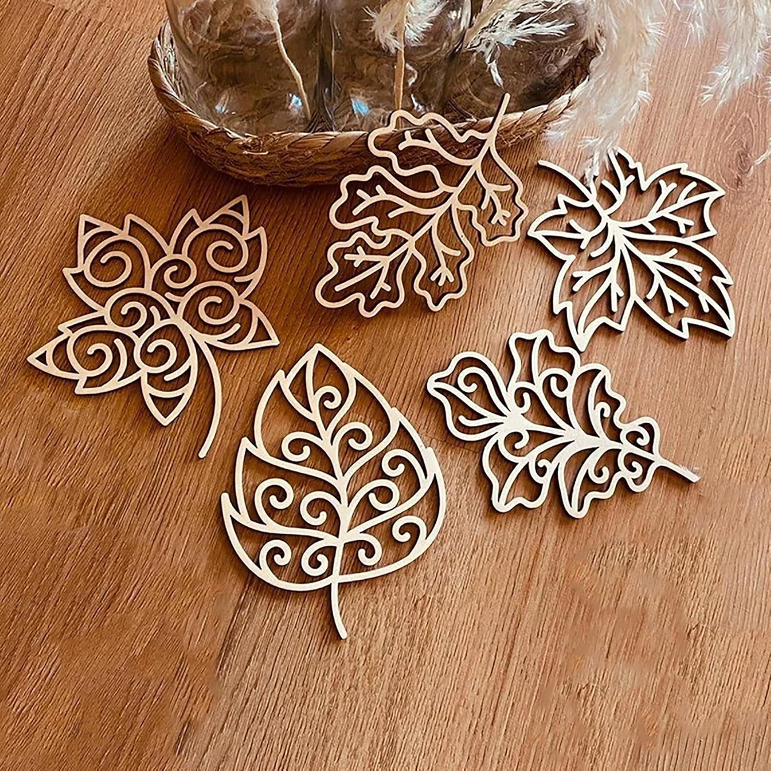 Decorative leaf-shaped cutouts on a wooden surface with a basket in the background.