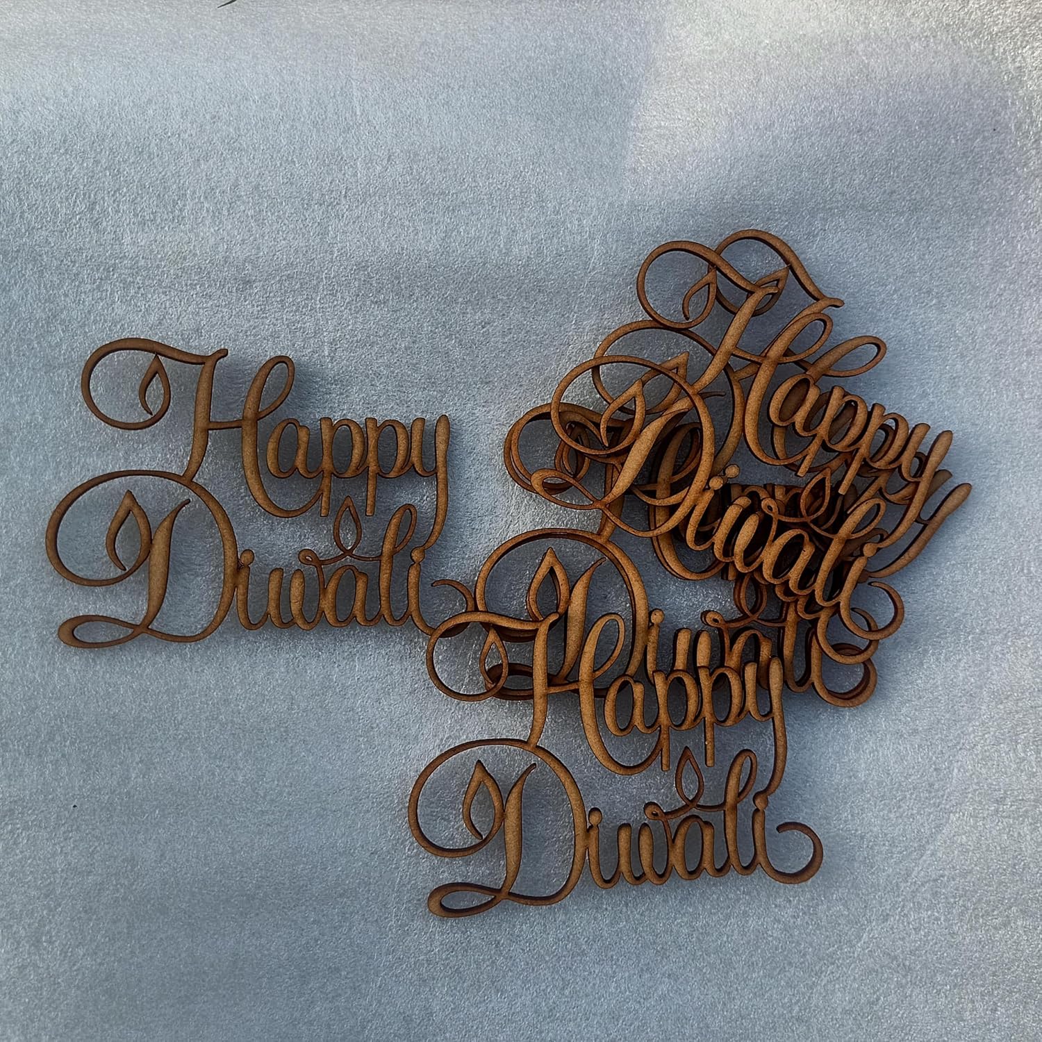 Wooden decorative pieces with 'Happy Diwali' text on a light blue background