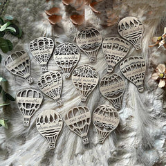 Wooden hot air balloon-shaped ornaments with milestone inscriptions on a textured surface.
