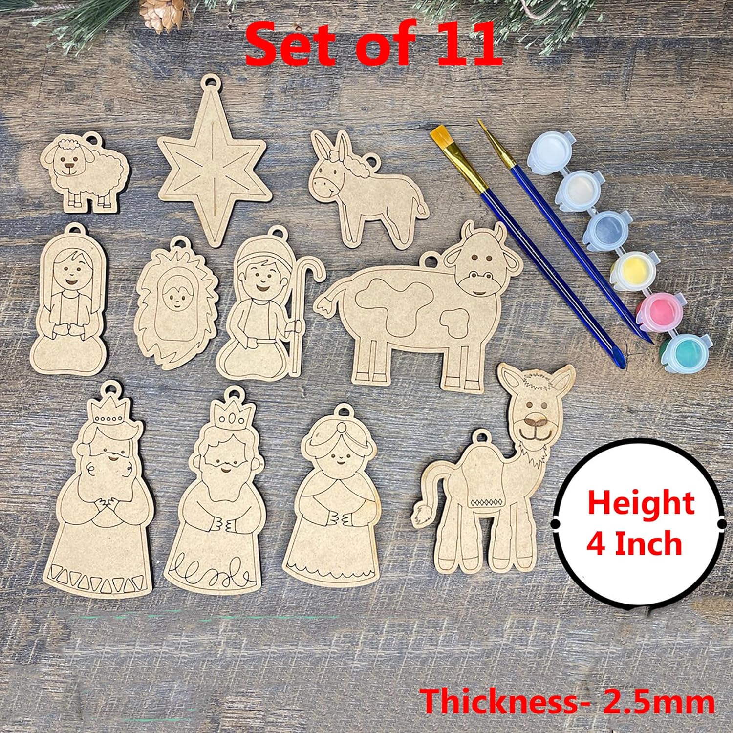 Set of 11 wooden Christmas nativity scene ornaments with paintbrush and paint on a wooden surface.