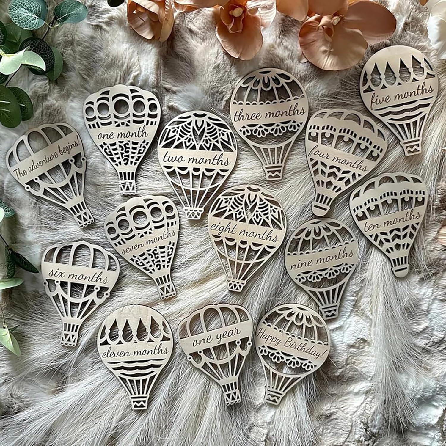 Wooden hot air balloon-shaped milestones with milestone text on a fur background