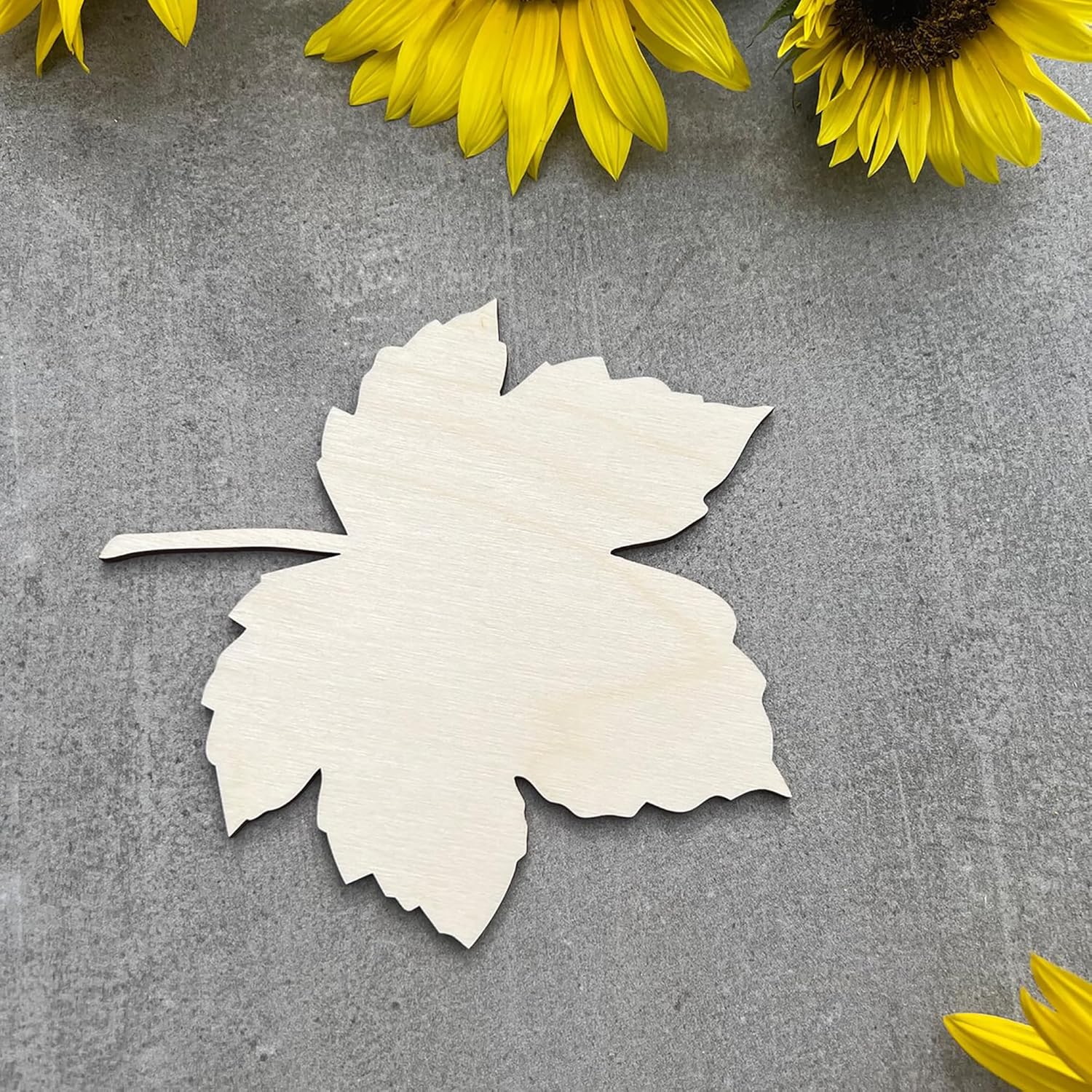 White paper leaf on a gray surface with sunflowers in the background