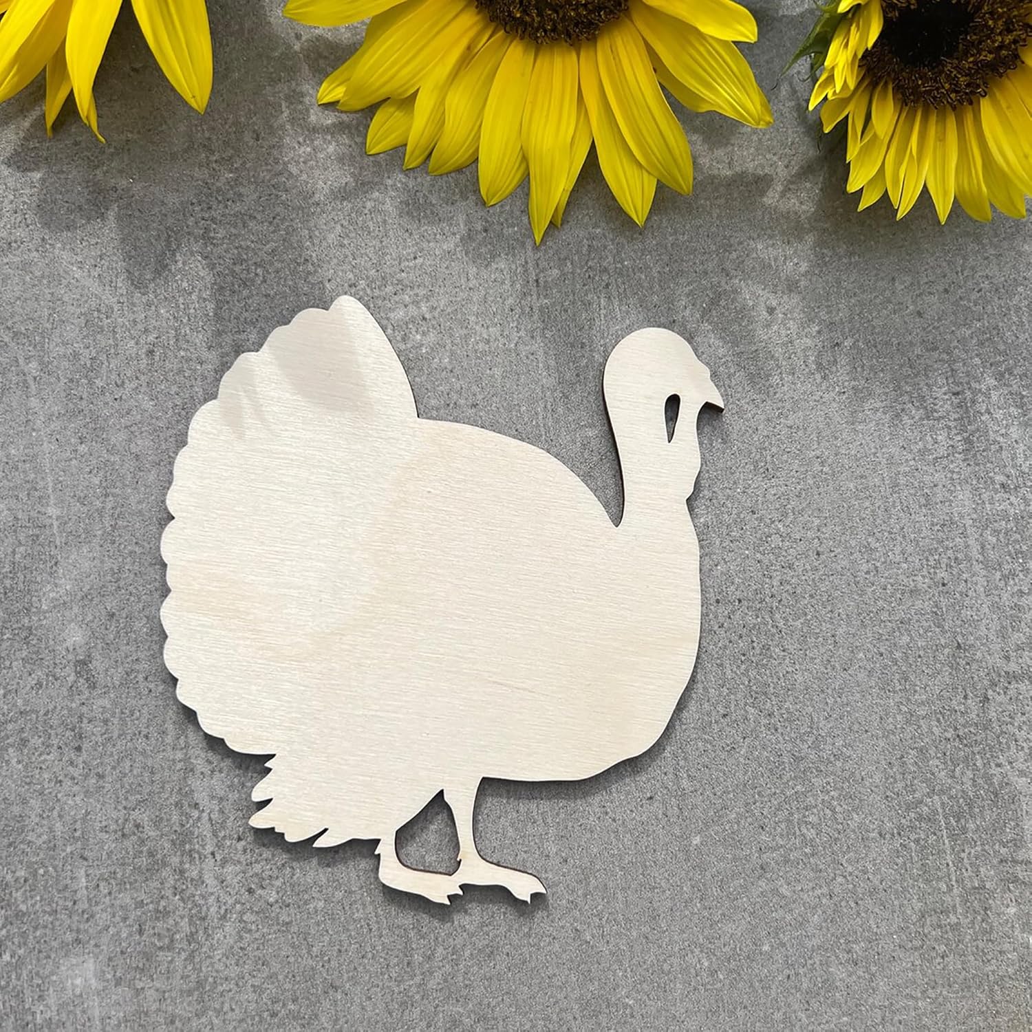 White turkey cutout on a gray surface with yellow sunflowers in the background