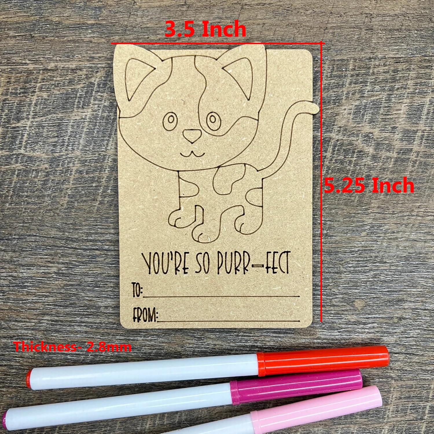 Kraft paper card with cat design and measurements on a wooden surface, with markers below.