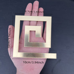 Gold square frames of different sizes held in a hand against a dark background