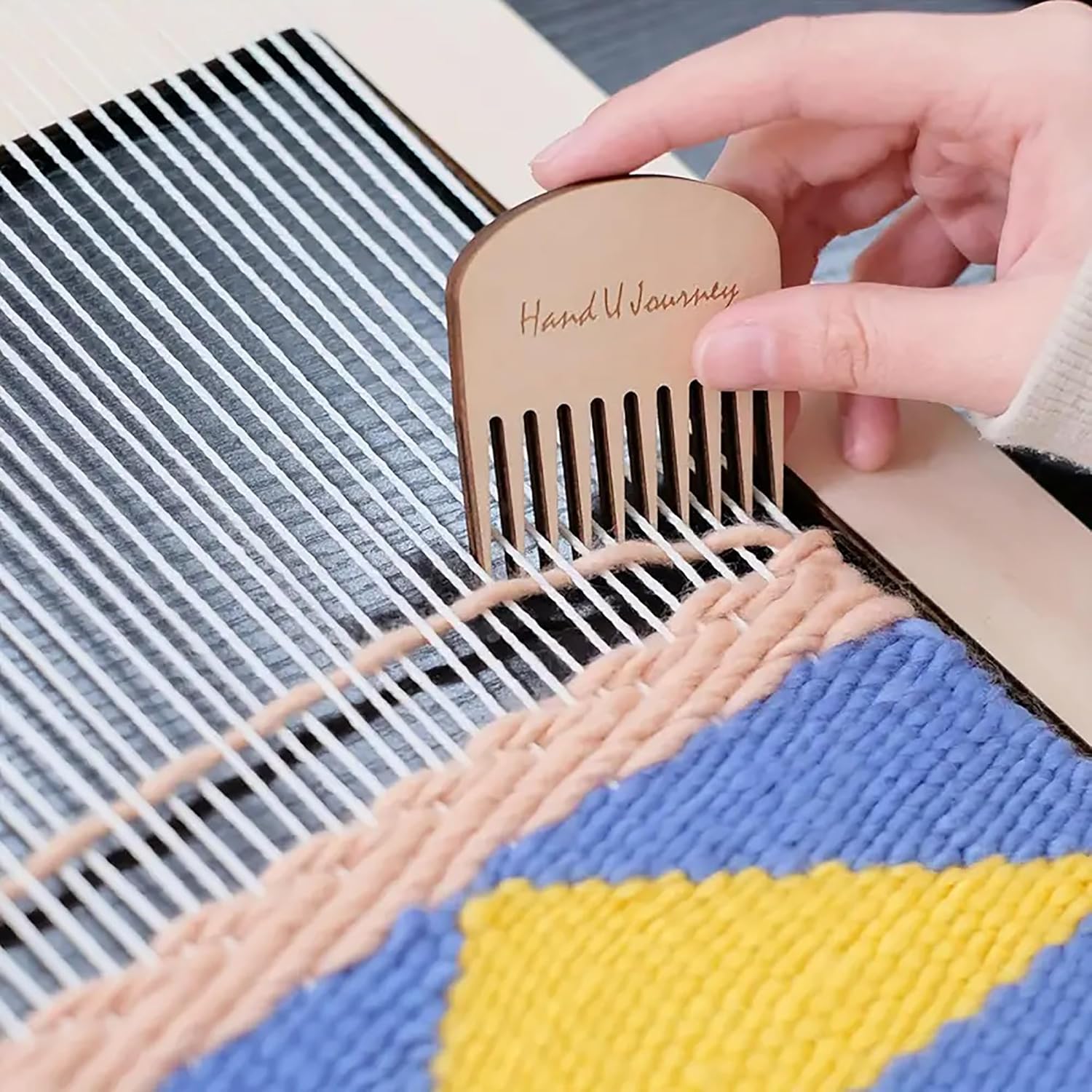 Handmade wooden comb being used on a woven fabric with 'Hand Wovenery' branding.