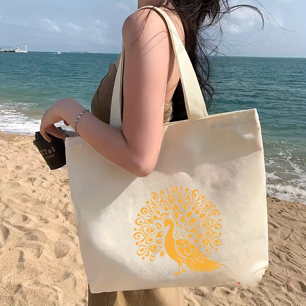 Person holding a tote bag with a peacock design on a beach