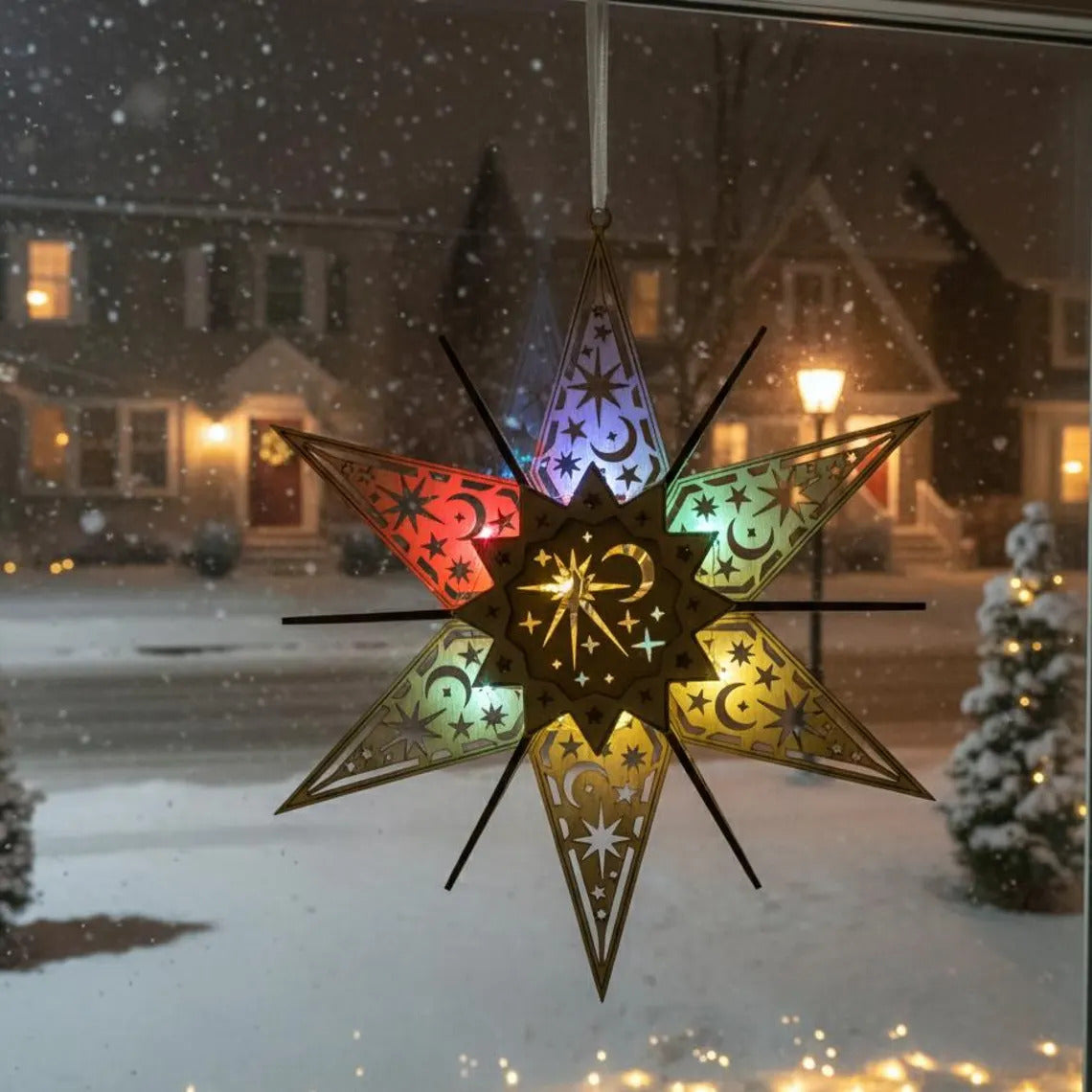 Decorative star-shaped window hanging with colorful patterns in front of a snowy street scene.